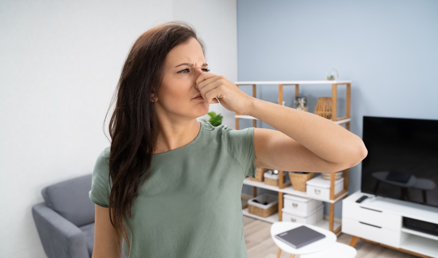 Woman covering her nose from bad smell inside the house